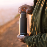 Close up of man holding the Klean Kanteen 12oz insulated drinks bottle at sunset