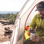 Man sat in a white tent holding the Klean kanteen stainless steel camp mug