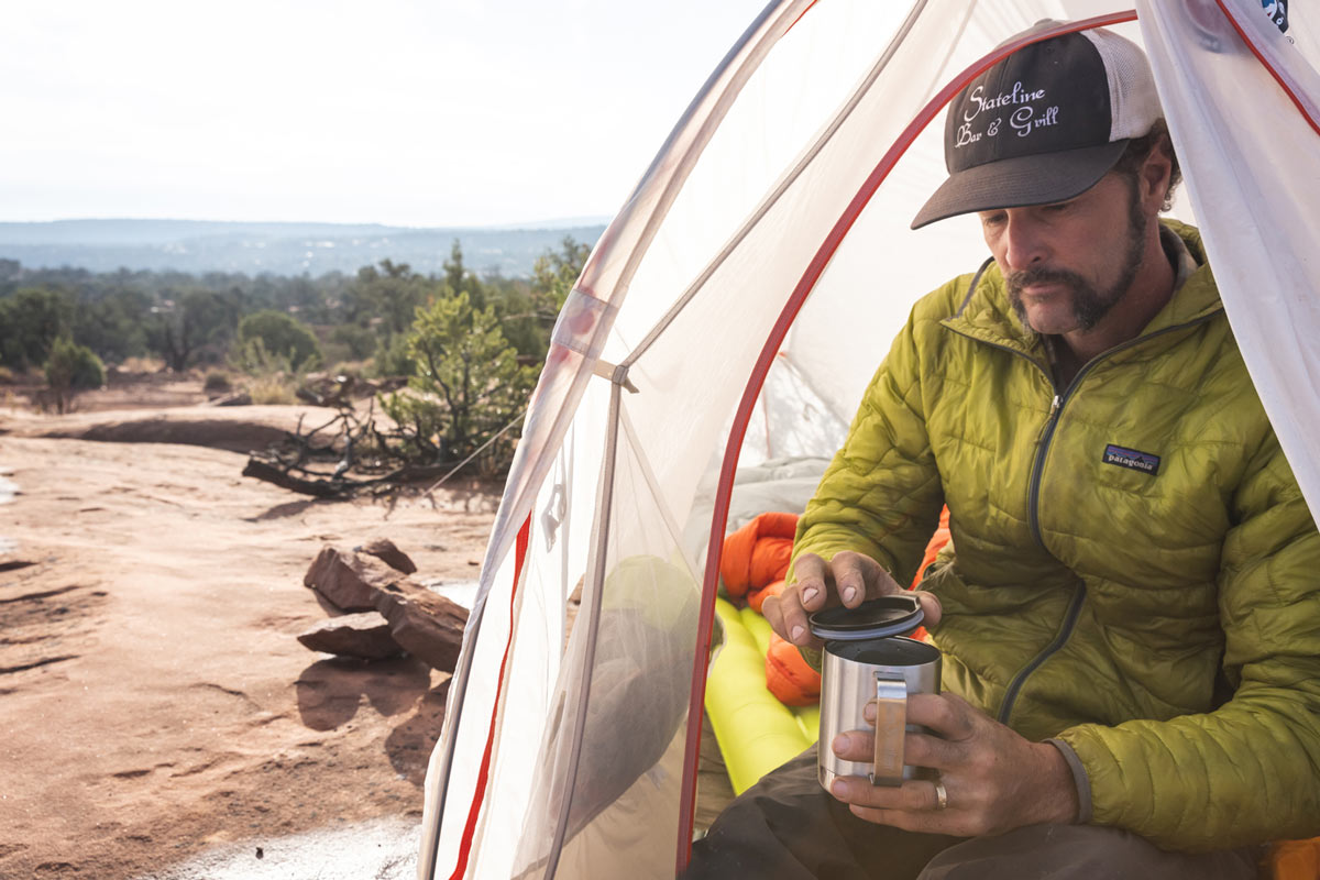 Man sat in a white tent holding the Klean kanteen stainless steel camp mug