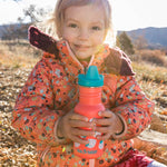 Girl sat on some rocks holding a Klean Kanteen 12oz kids sippy drinks bottle 