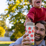 A child reaching for a Klean Kanteen 12oz Tofu Strawberries Print TKWide from an adult. The child is sitting on the adult's shoulders.  