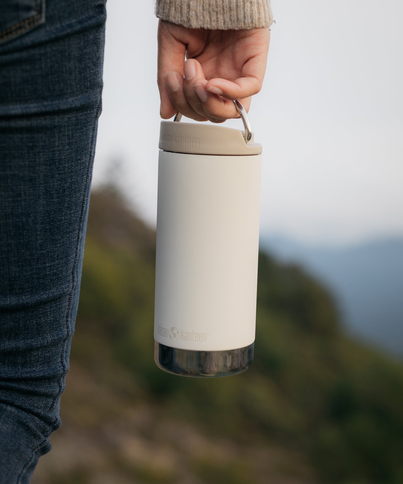 A close up of a person's hand carrying a Klean Kanteen 12oz TKWide Cafe in the tofu colour.