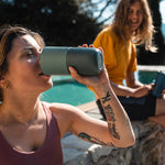 Close up of woman drinking from a Klean Kanteen stainless steel drinks tumbler next to a stone wall