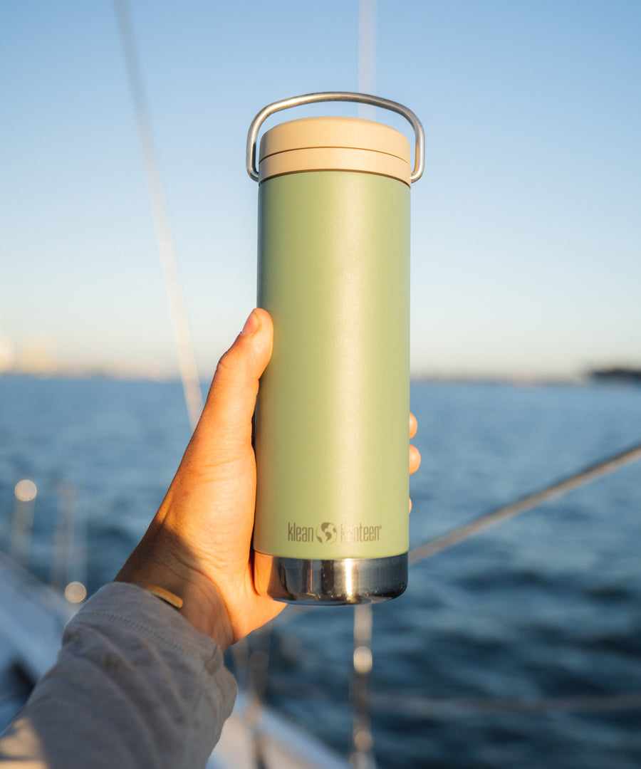 A close up of a person holding up a sea spray green coloured Klean Kanteen 20oz TKWide .