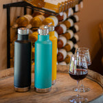 3 klean kanteen 750ml classic insulated bottles with the pour through cap on a wooden barrel next to some glasses of red wine