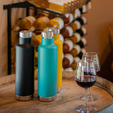 3 klean kanteen 750ml classic insulated bottles with the pour through cap on a wooden barrel next to some glasses of red wine