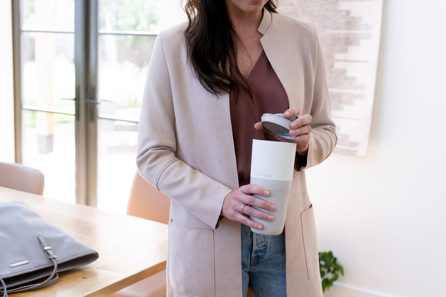 Close up of woman holding the removable flip lid above her Klean Kanteen 26oz insulated drinks tumbler