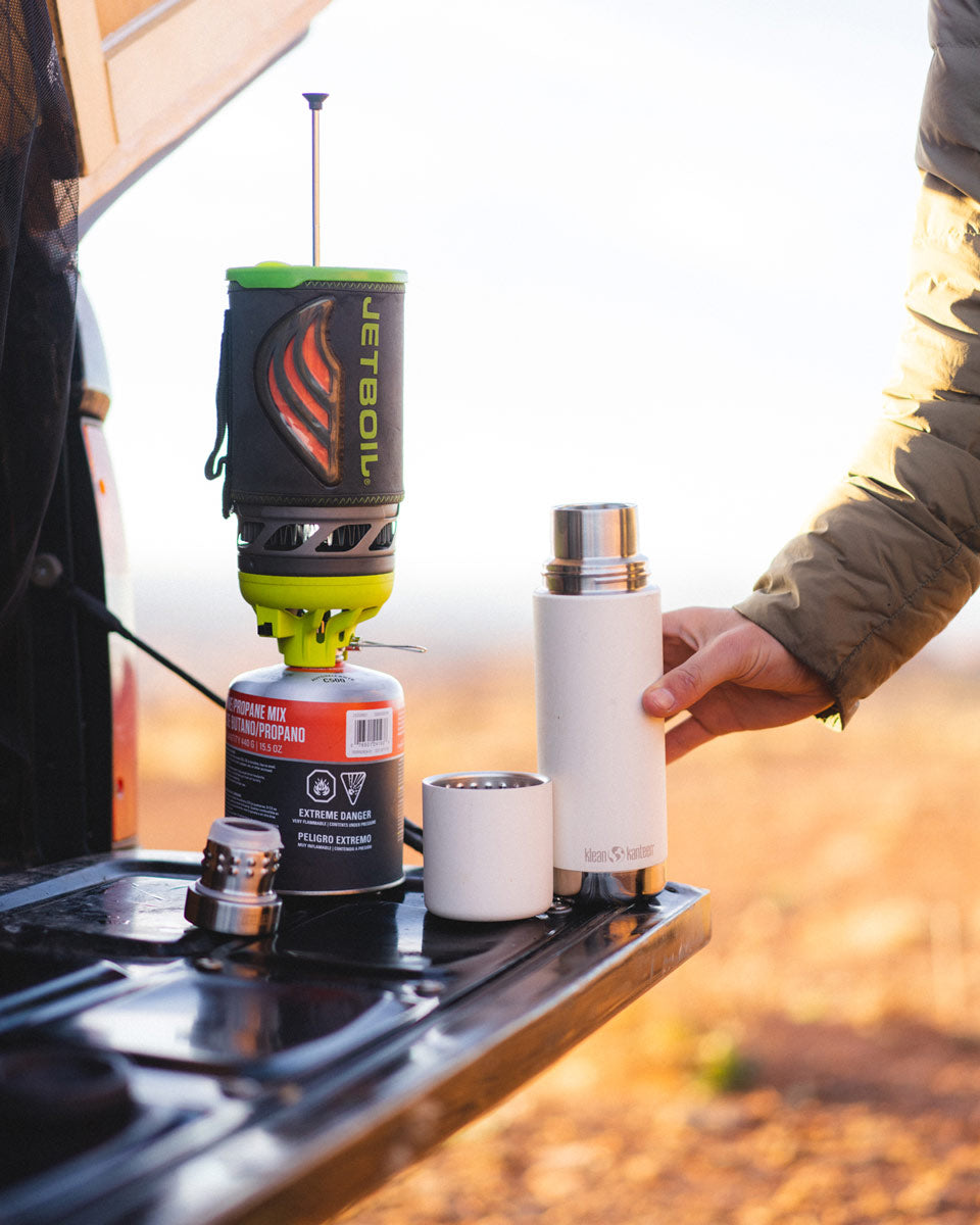 Close up of a Klean kanteen reusable tkpro flask on a car tailgate next to some camping equipment