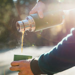 Close up of some hands pouring hot liquid into the cup of a Klean kanteen 25oz insulated tkpro flask