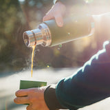 Close up of some hands pouring hot liquid into the cup of a Klean kanteen 25oz insulated tkpro flask