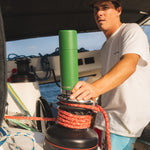 Man stood driving a boat and holding onto a Klean kanteen reusable stainless steel tkpro flask