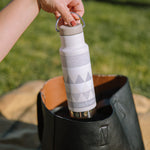 Close up of womans hand pulling a Klean Kanteen stainless steel insulated bottle from a handbag