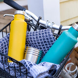 2 klean kanteen classic insulated pour through bottles in a bike basket next to some steel cups