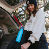 Girl putting the Klean kanteen 18oz reusable metal sports bottle in the side pocket of a backpack