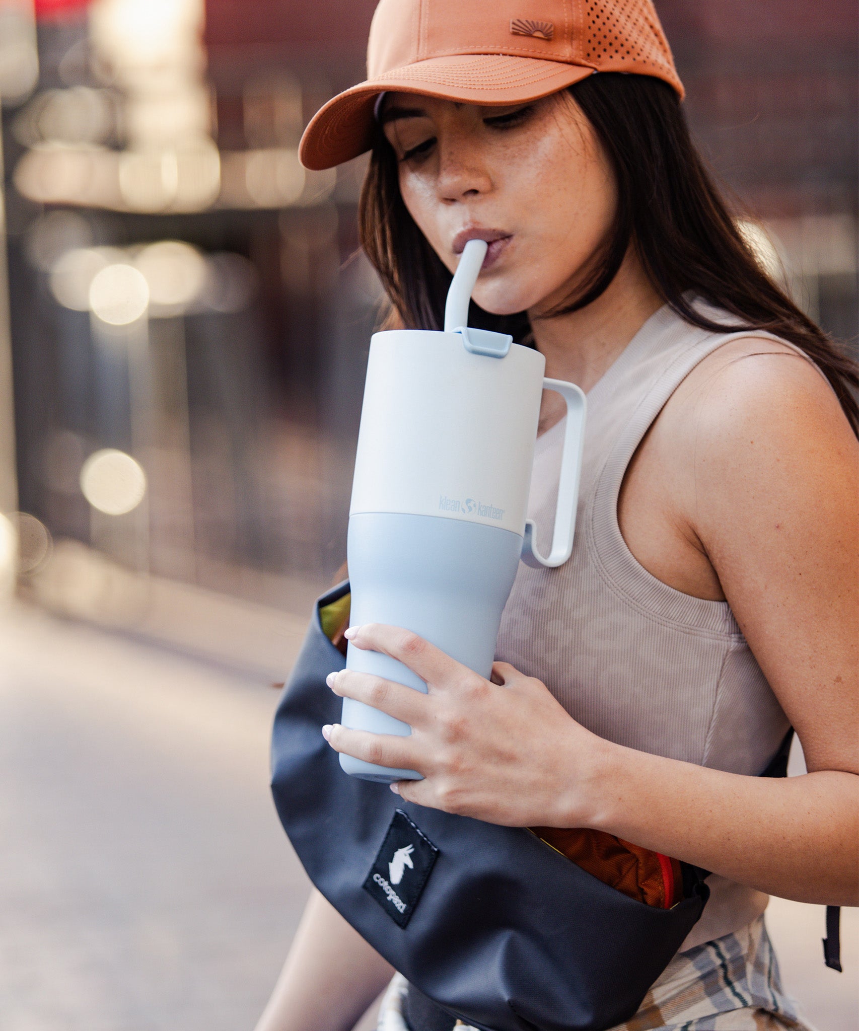 A person holding the icy blue colour Klean Kanteen Limited Edition 36oz Rise Tumbler whilst sipping through the silicone tipped straw