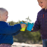 Close up of hands pouring water from a Klean Kanteen TKPro flask into some Kid Kanteen stainless steel drinking cups