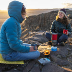 Two adults enjoying the sunset and laughing. Both are holding their Klean Kanteen Camping Mugs