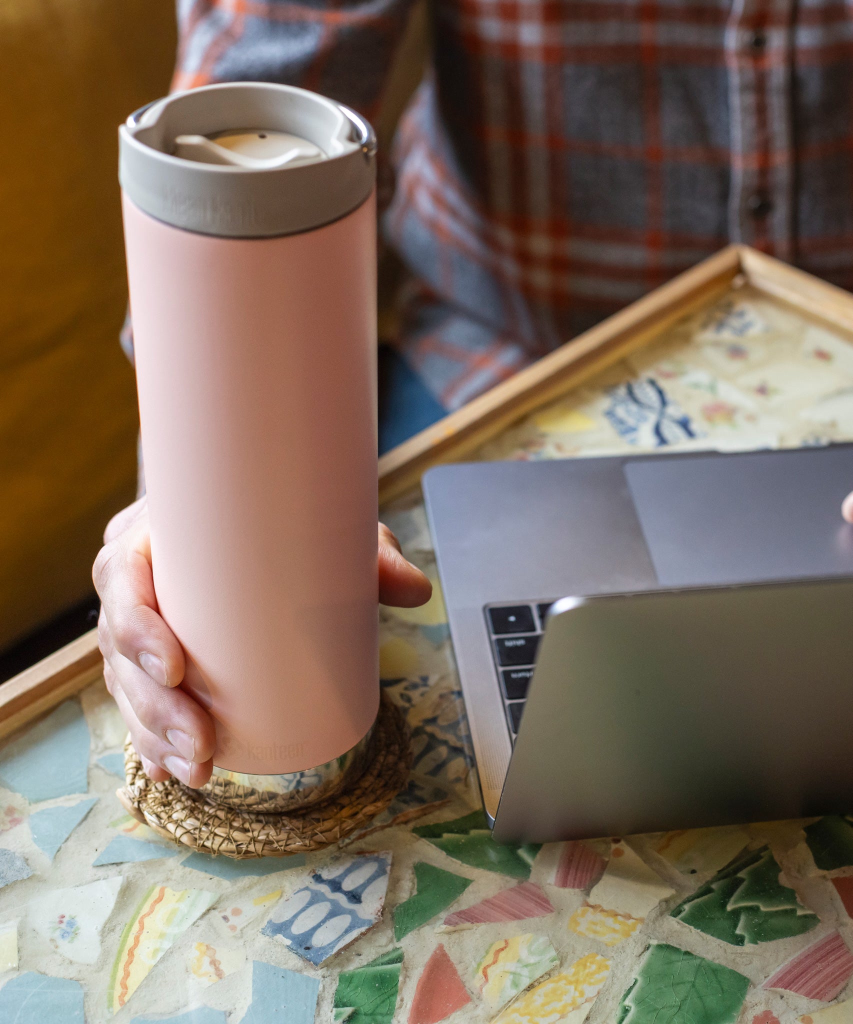 A close up of a person's hand holding onto the peack parfait pink coloured Klean Kanteen 20oz TKWide Cafe.