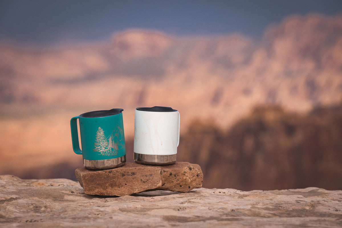 Close up of 2 Klean kanteen eco-friendly metal travel mugs balanced on a rock 