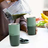 Close up of person pouring a green smoothie from a jug into a Klean Kanteen green stainless steel 16oz tumbler