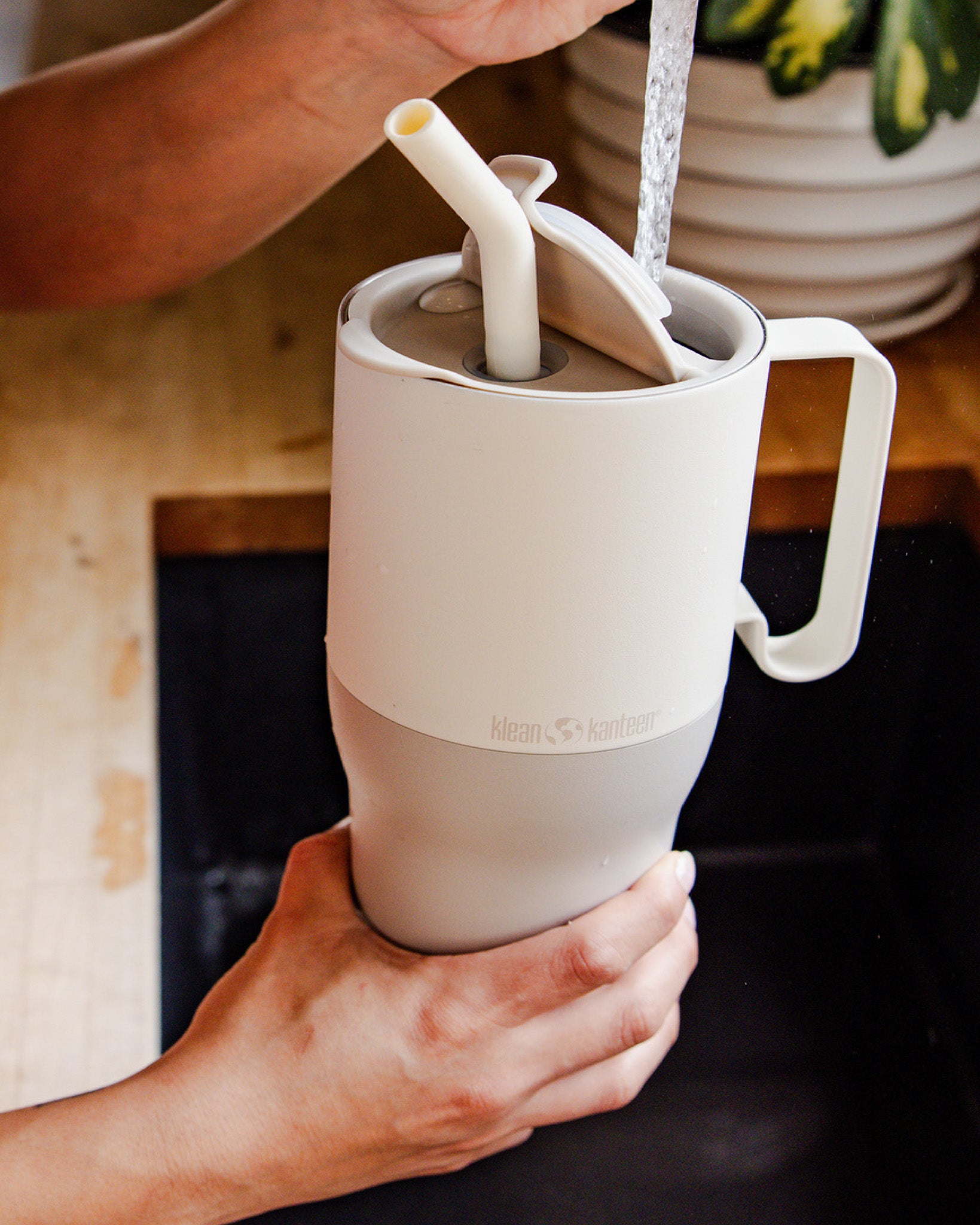 A close up of a person filling up a Tofu coloured Klean Kanteen Limited Edition 36oz Rise Tumbler with water from a tap