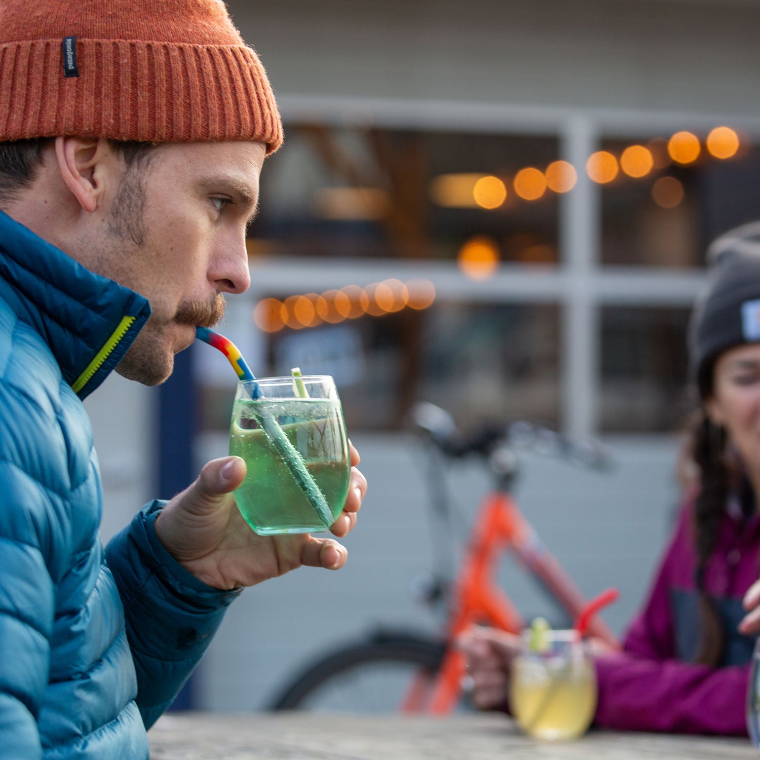 An adult drinking from a short glass using one of the short Klean Kanteen Stainless Steel Straws