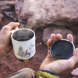 Close up of hands holding the Klean kanteen eco-friendly metal camp mug in the matte white mountain colour