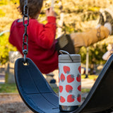 A Klean Kanteen 12oz Tofu Strawberries Print TKWide placed on a swing. A child can be seen swinging on another swing in the background. 