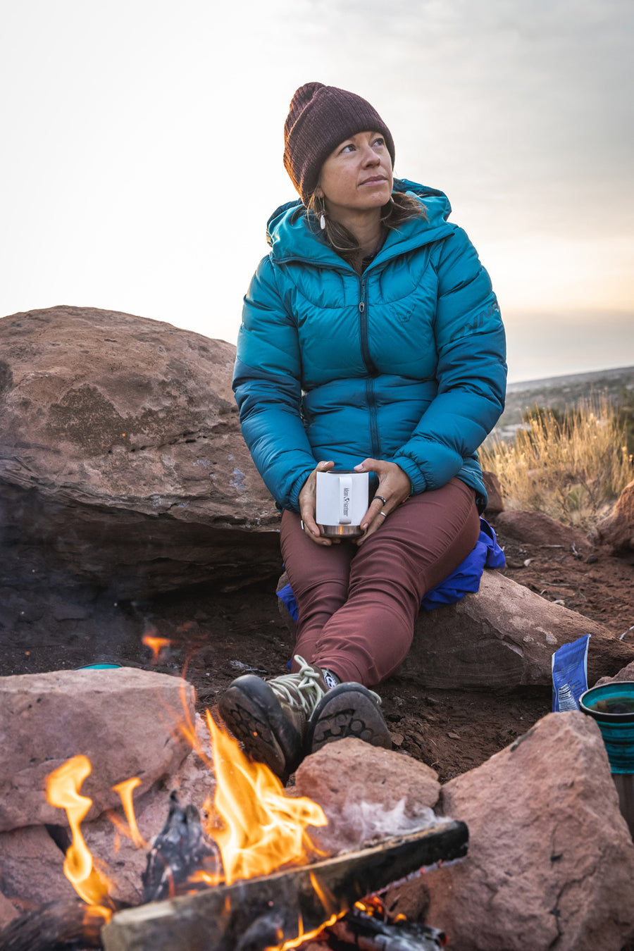 An adult sat outside by a fire