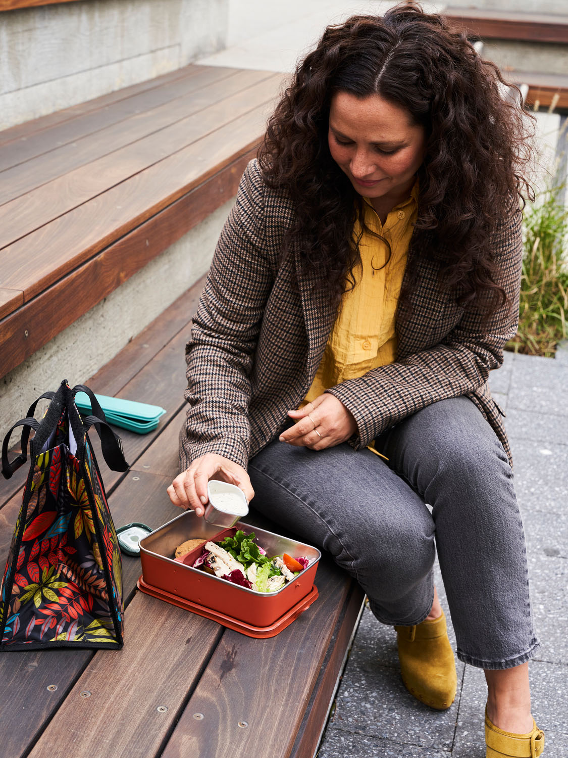 Person wearing a tweed jacket removing the Klean Kanteen Rise Stainless Steel Half Snack Box containing a salad dressing from a Big Meal Box (available separately from Babipur) filled with a delicious salad