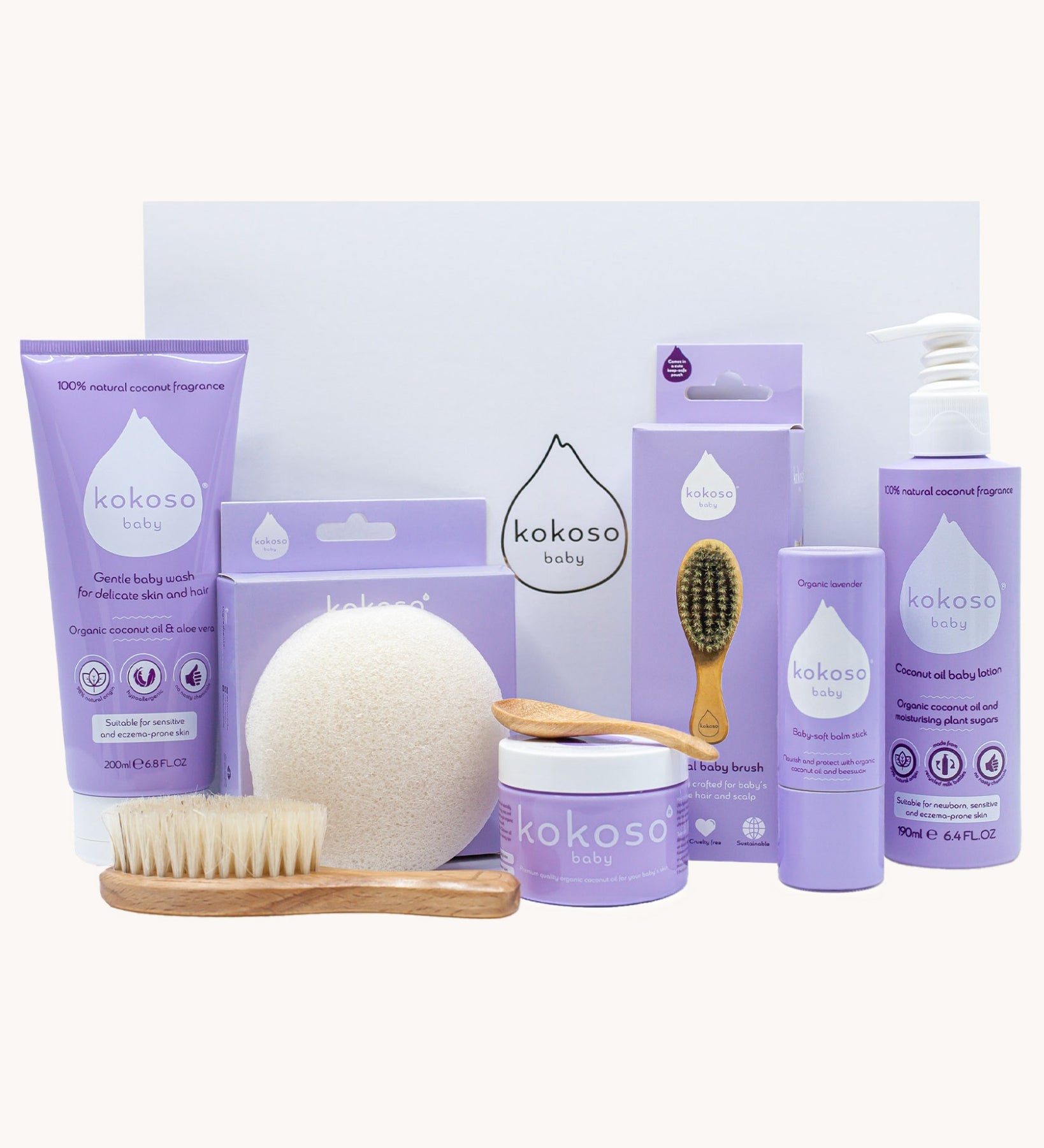 Kokoso Scented Baby Collection - Coconut & Lavender, showing the contents of the Collection. Cocont Oil, Baby Soft Balm Stick, Gentle Hair & Body Wash, Coconut Oil Baby Lotion, Natural Brush, and a Sponge. The items are displayed on a cream background