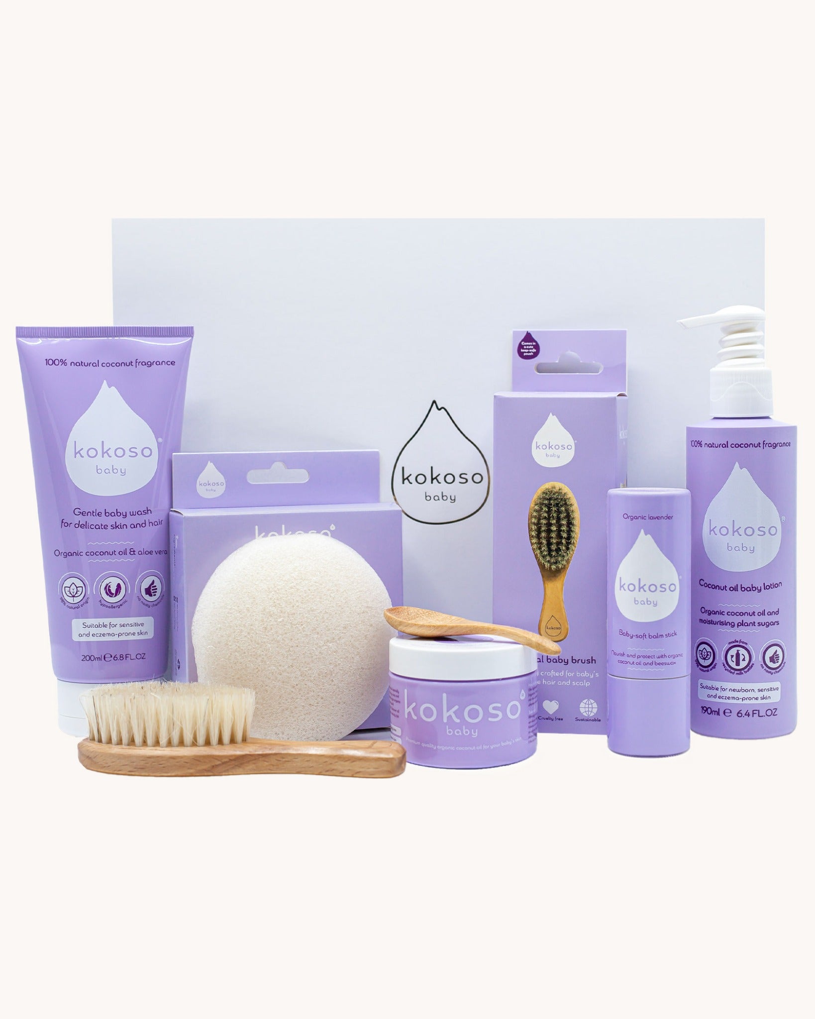 Kokoso Scented Baby Collection - Coconut & Lavender, showing the contents of the Collection. Cocont Oil, Baby Soft Balm Stick, Gentle Hair & Body Wash, Coconut Oil Baby Lotion, Natural Brush, and a Sponge. The items are displayed on a cream background