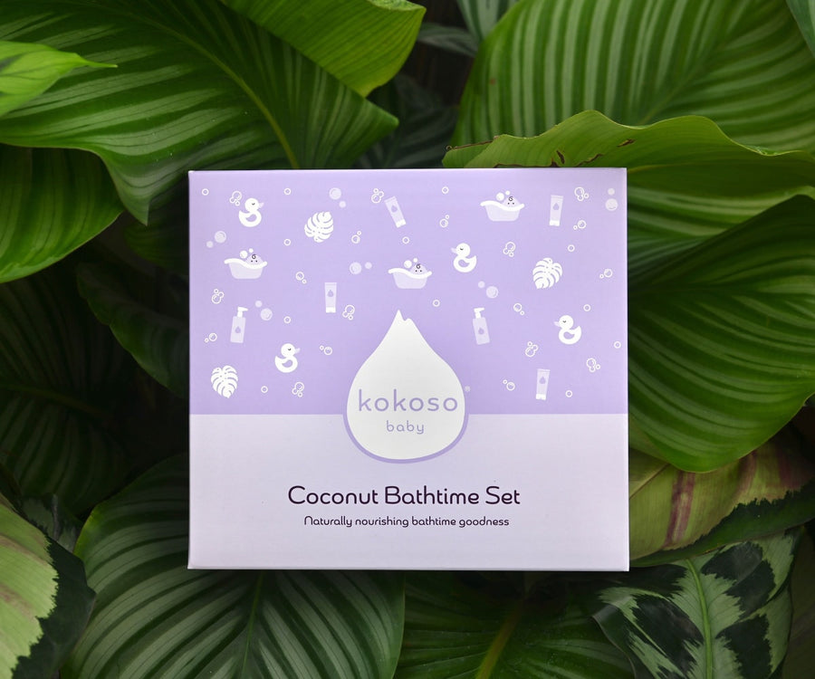 with 2 green ribbons and scissors ready for wrapping. A Kokoso Coconut Bathtime Organic Baby Gift Set box with contents laid out on the paper. Contents are Kokoso Natural Baby Konjac Sponge