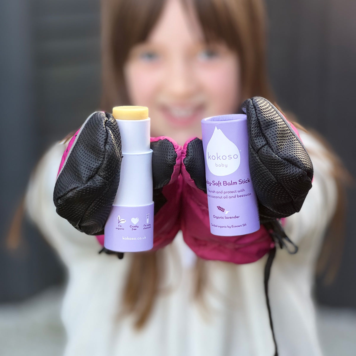 Close up of a child holding up a Kokoso organic coconut oil baby balm stick