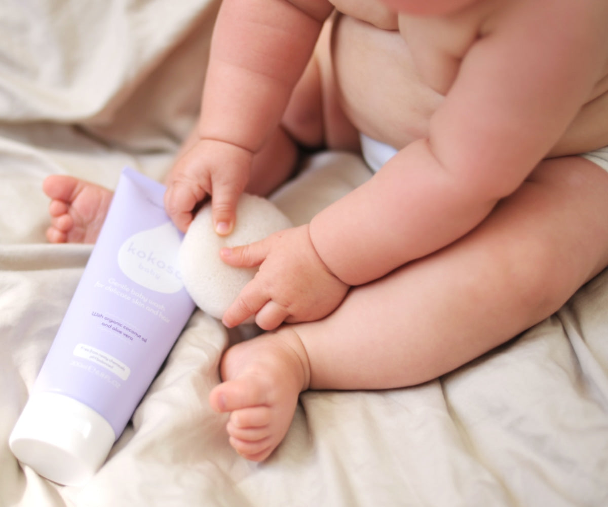 Chubby baby sits on sheet