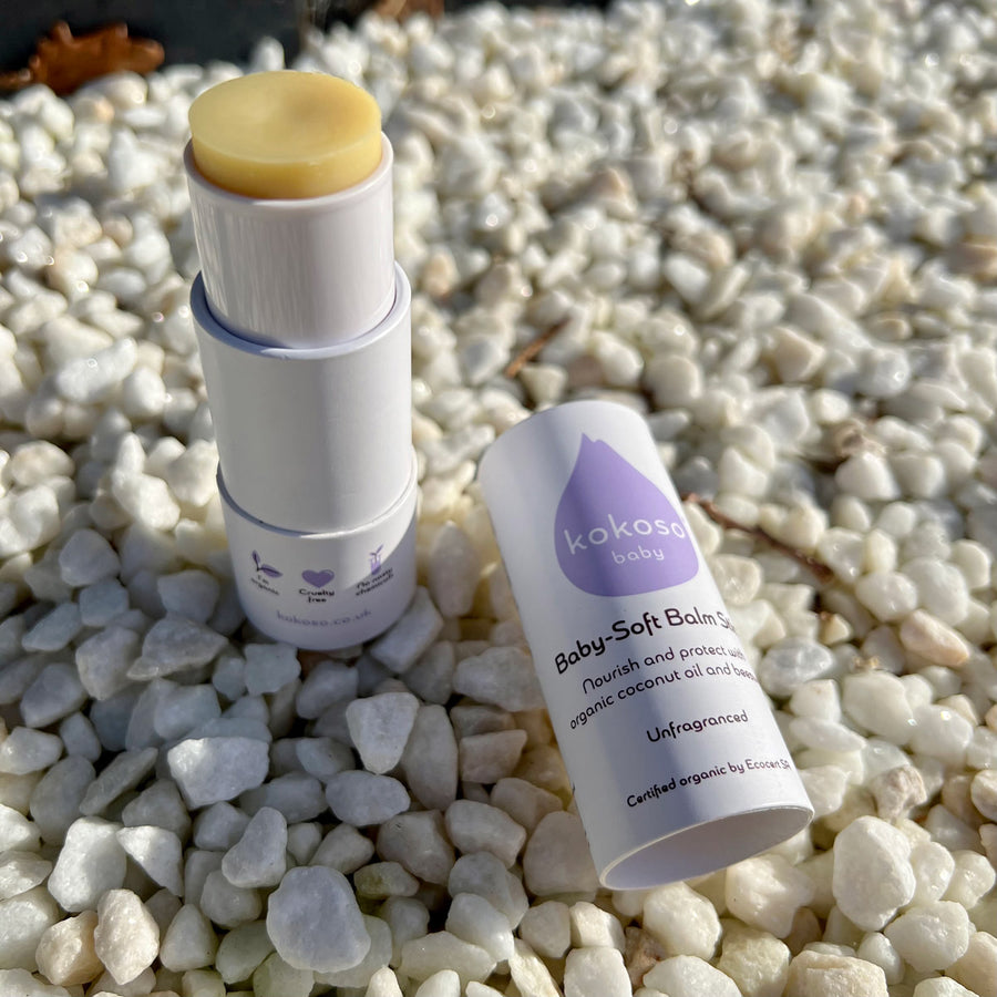 Close up of an unfragranced Kokoso baby balm stick on some white stones