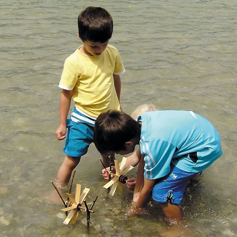 Children playing with the Kraul small waterwheel kit in a river.