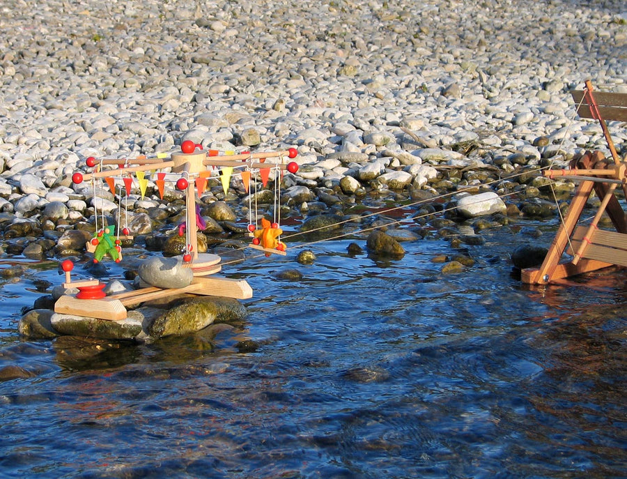 Kraul Wooden Swing Roundabout Kit with passenger dolls in a river