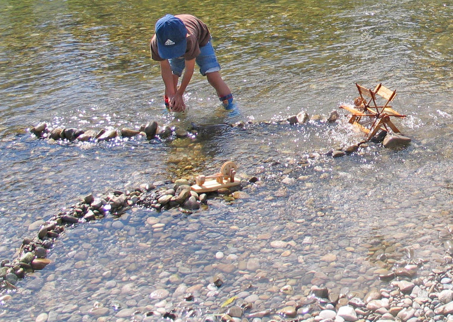 Child playing with Kraul Wooden River Wheel in river