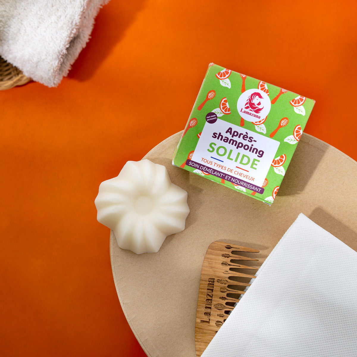 Lamazuna Detangling & Nourishing Solid Conditioner Bar pictured next to box and a wooden comb and towel