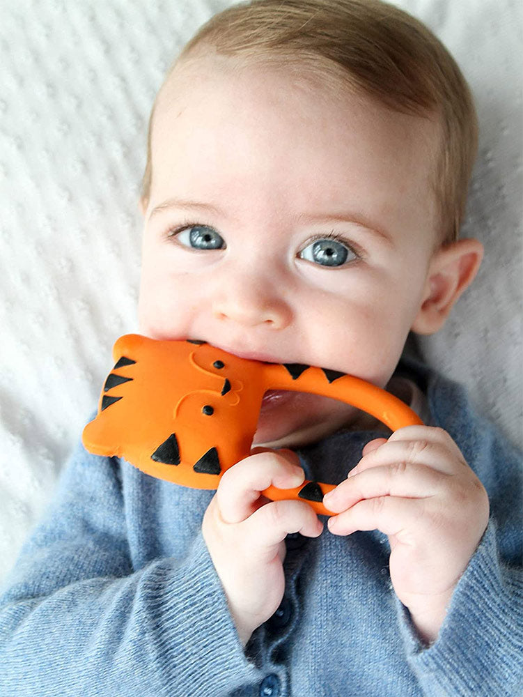 A baby holding and chewing on the Lanco Nalu the Tiger Teether