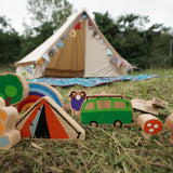 Close up of the Lanka Kade dan y ser wooden toy set on some grass in front of a beige tent