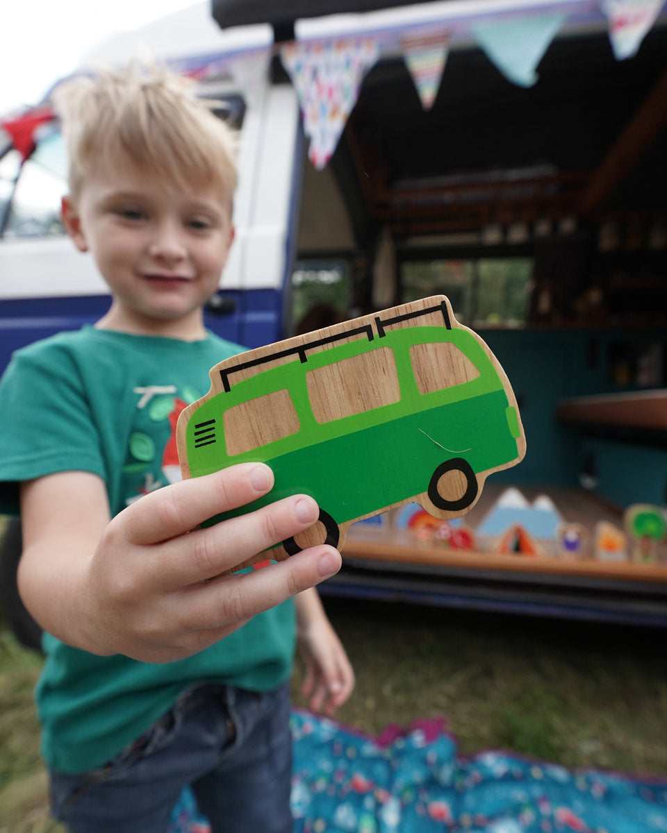 Close up of a boy holding the Lanka Kade lola campervan vehicle toy in front of a blue campervan