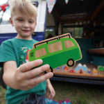 Close up of a boy holding the Lanka Kade lola campervan vehicle toy in front of a blue campervan