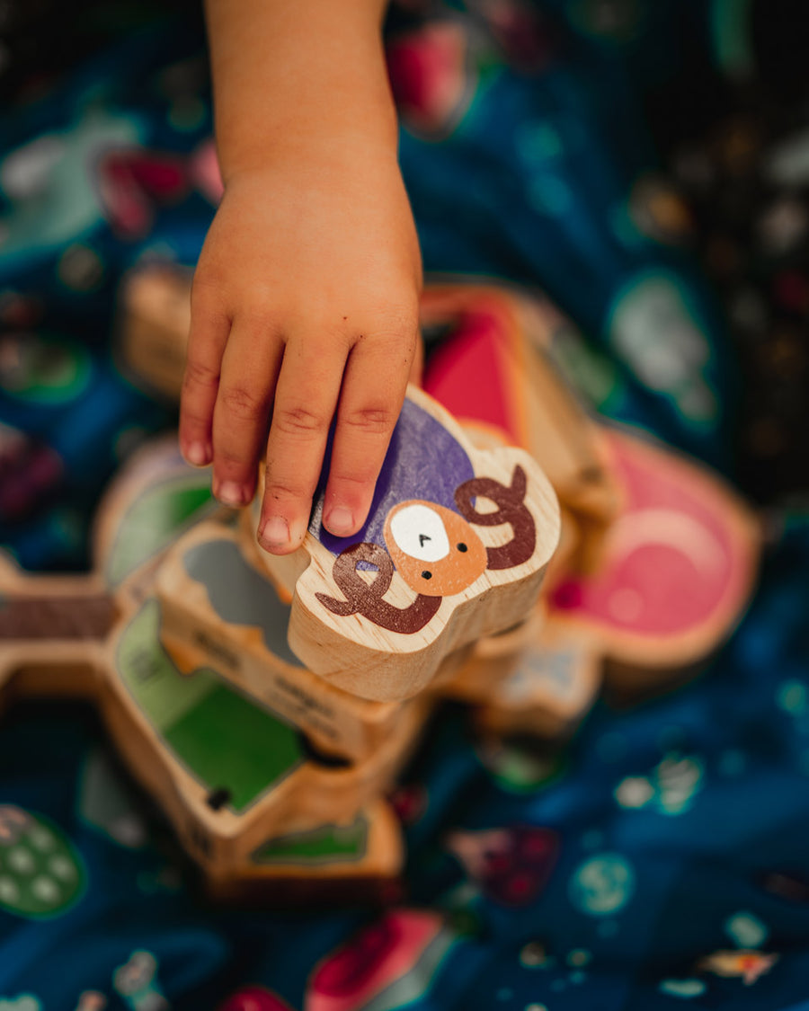 Close up of hand grabbing the Lanka Kade purple ram animal toy on a dan y ser playmat