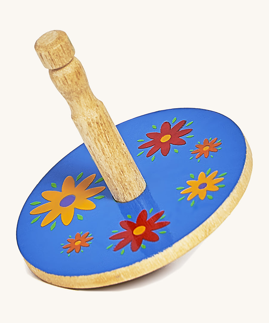 A yellow wooden Lanka Kade spinning top with red and yellow flowers on a cream background.