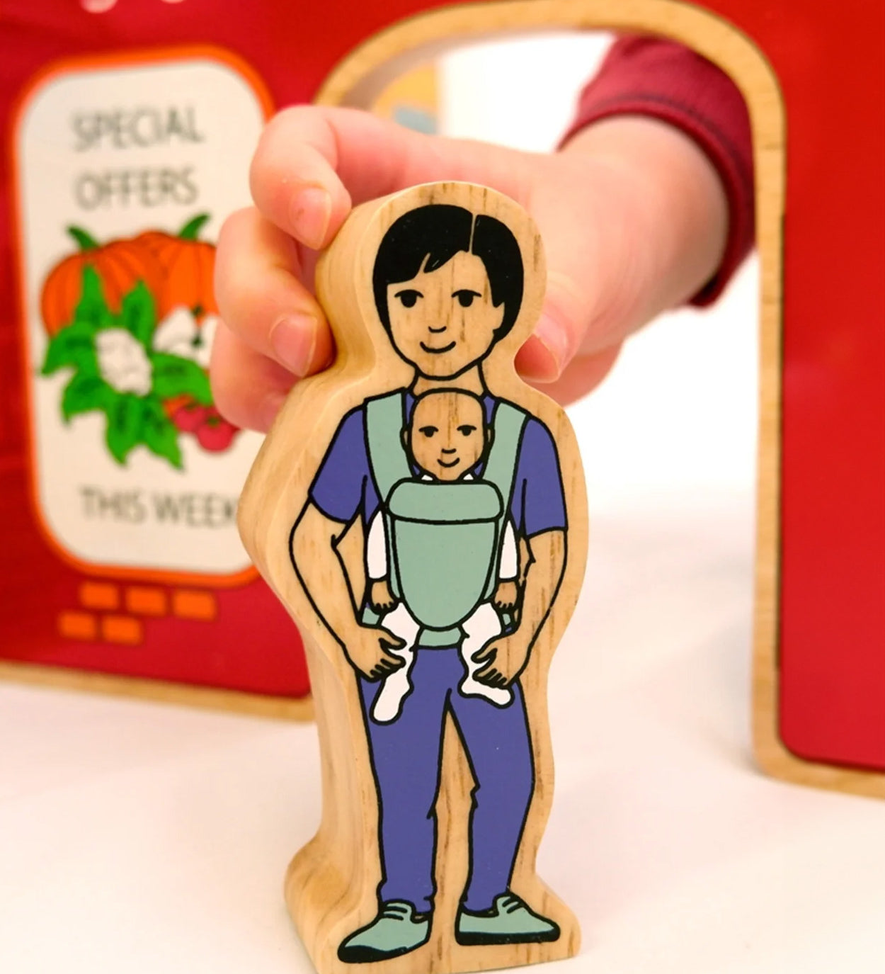 A babywearing person from the Lanka Kade community wooden toy figure playset. 