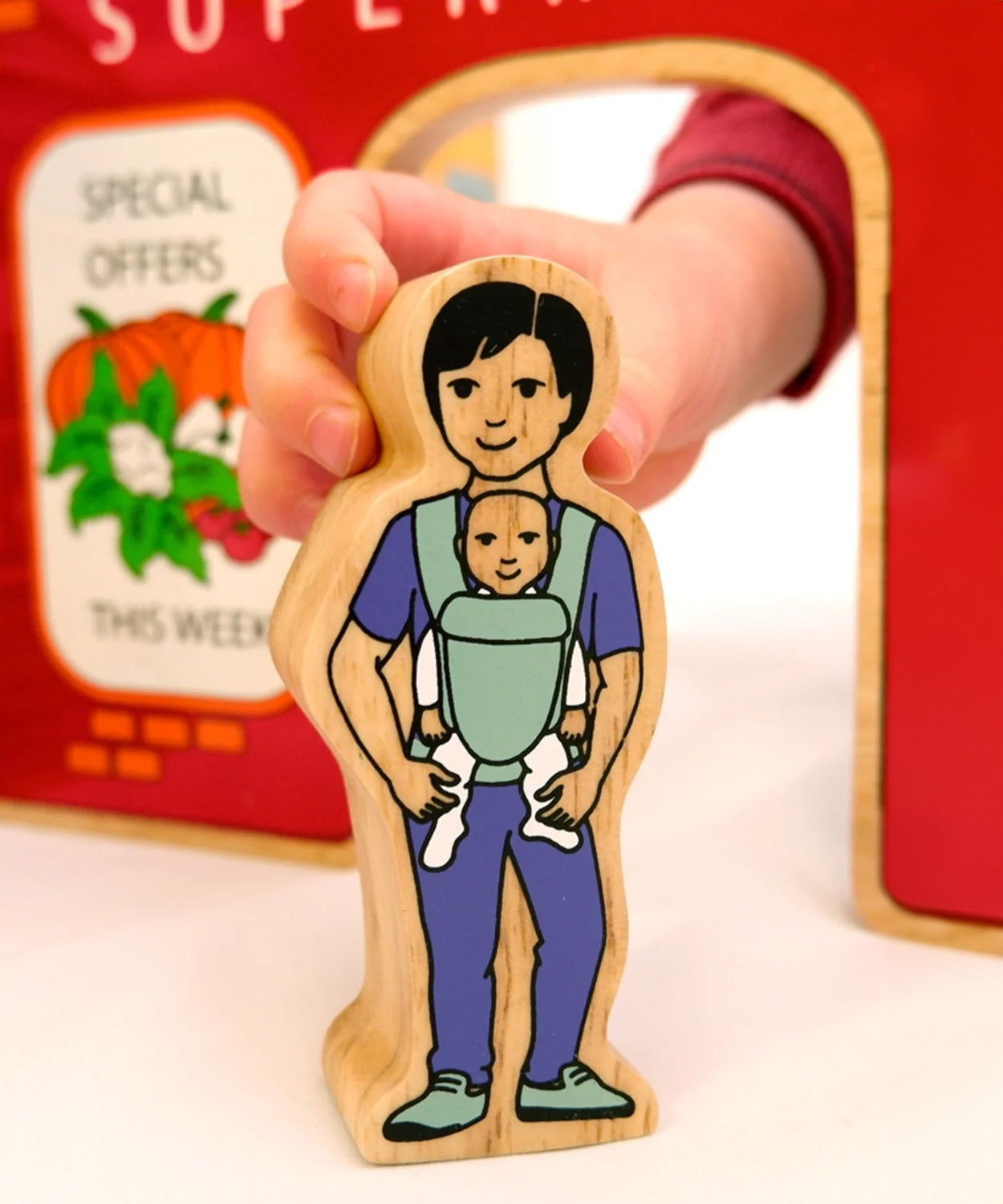 A babywearing person from the Lanka Kade community wooden toy figure playset. 