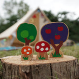 Close up of the Lanka Kade dan y ser toadstool toys on a wooden log in front of a beige tent