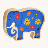 A blue wooden Lanka Kade elephant with yellow and red flowers on a cream background.